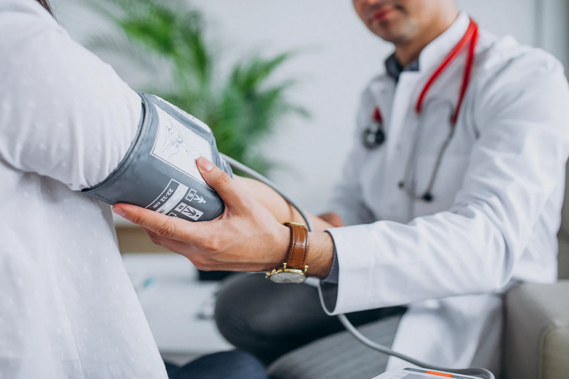 Young male physician checking patient’s blood pressure during medical consultation for heart health assessment.